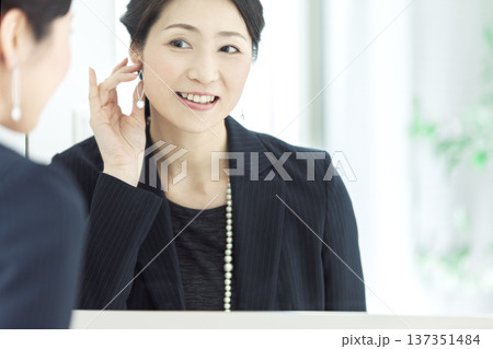 鏡の前でイヤリングをつける女性 137351484