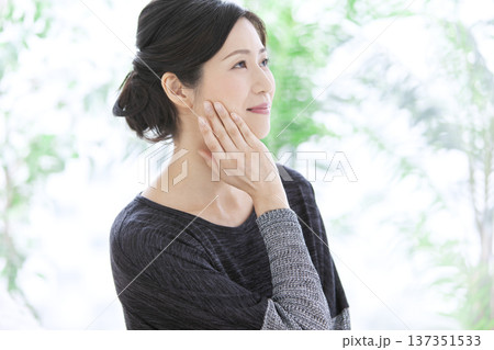 顔に手をあてる中年女性 顔に手をあてる中年女性 137351533