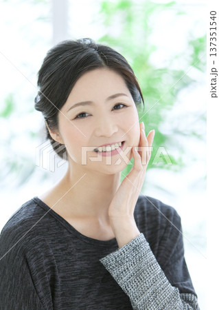 顔に手をあてる中年女性 顔に手をあてる中年女性 137351540