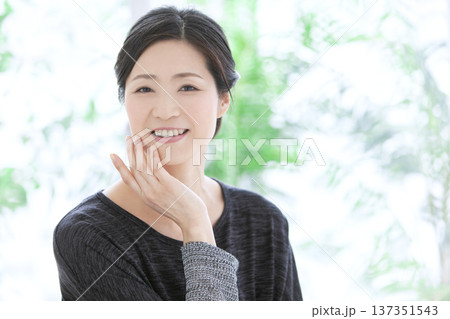 顔に手をあてる中年女性 顔に手をあてる中年女性 137351543