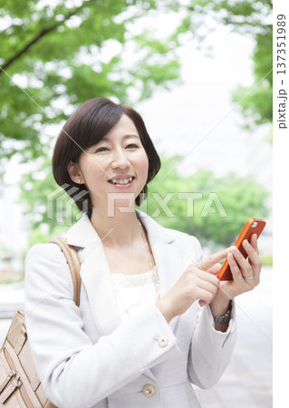 携帯電話を操作するキャリアウーマン 携帯電話を操作するキャリアウーマン 137351989