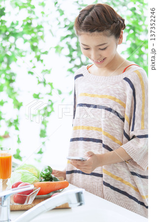 キッチンでスマートフォンを操作する女性 137352246