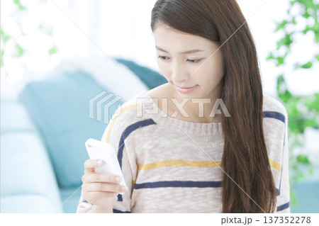 ソファでスマートフォンを操作する女性 137352278