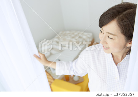 カーテンを開けるパジャマ姿の中年女性 カーテンを開けるパジャマ姿の中年女性 137352357