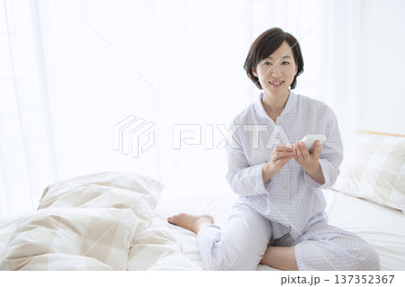 ベッドでスマートフォンを操作する女性 137352367