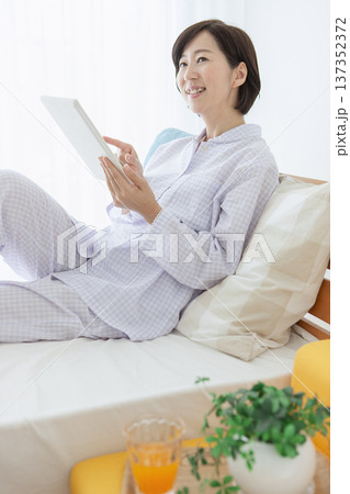 ベッドでタブレットを操作する女性 ベッドでタブレットを操作する女性 137352372