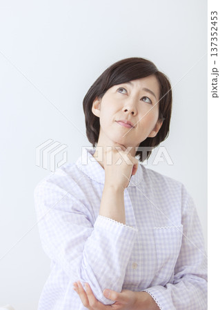 考え事をするパジャマ姿の中年女性 137352453