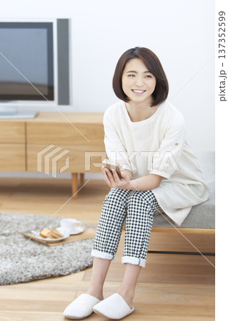 リビングでスマートフォンを操作する女性 リビングでスマートフォンを操作する女性 137352599