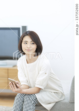 リビングでスマートフォンを操作する女性 137352600
