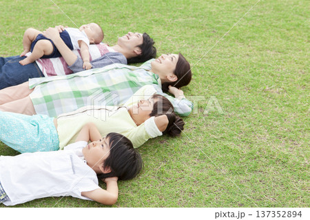 芝生に寝転ぶ家族 137352894