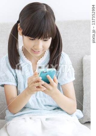 ソファでスマートフォンを操作する女の子 ソファでスマートフォンを操作する女の子 137352994