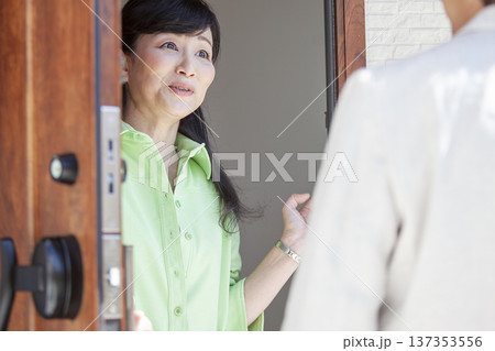 玄関先で話す夫婦 玄関先で話す夫婦 137353556