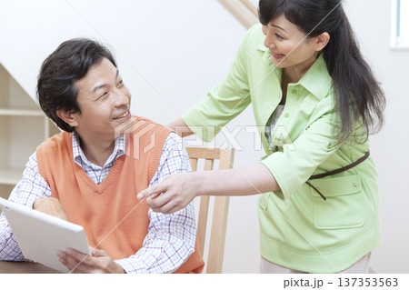 タブレットを見て話す夫婦 タブレットを見て話す夫婦 137353563