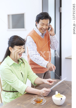 タブレットを見て話す夫婦 タブレットを見て話す夫婦 137353565