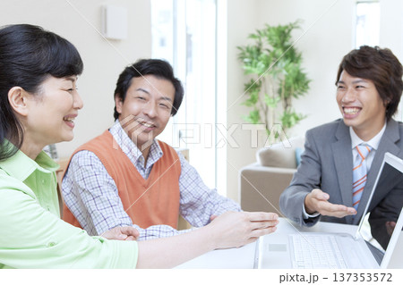 営業マンと打ち合わせをする夫婦 137353572