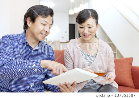 タブレットを見て話す夫婦 137353587