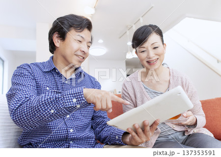 タブレットを見て話す夫婦 137353591