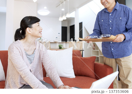 リビングでパソコンを見る夫婦 リビングでパソコンを見る夫婦 137353606