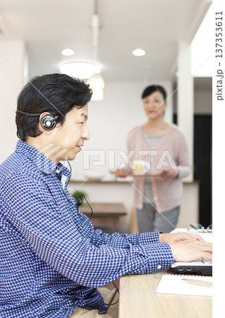 パソコンを操作する男性とお茶を運ぶ女性 137353611