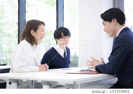 塾や学校で進路の面談を受ける親と子供 三者面談高校受験や大学受験のイメージ 塾や学校で進路の面談を受ける親と子供 三者面談高校受験や大学受験のイメージ 137354901