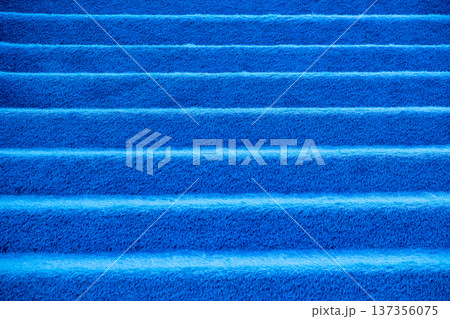 Blue carpeted stairs texture creating a repeating pattern and abstract background 137356075
