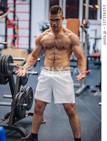 Strong sportsman flexing his muscles in a gym after an intense workout, showcasing dedication and power in russia's fitness scene Strong sportsman flexing his muscles in a gym after an intense workout, showcasing dedication and power in russia's fitness scene 137356353