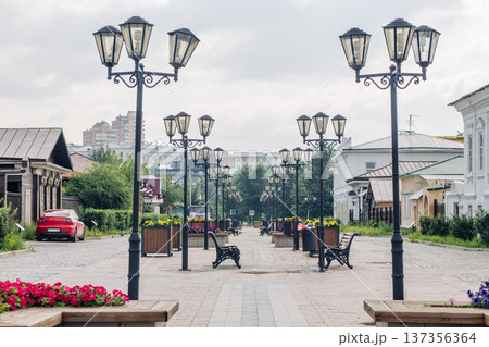 Cobblestone pedestrian street with benches and flowerbeds illuminated by elegant street lamps in irkutsk, russia Cobblestone pedestrian street with benches and flowerbeds illuminated by elegant street lamps in irkutsk, russia 137356364