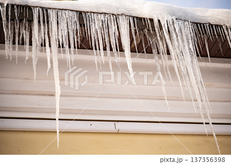 Icicles freezing on house roof eaves during cold winter weather season Icicles freezing on house roof eaves during cold winter weather season 137356398