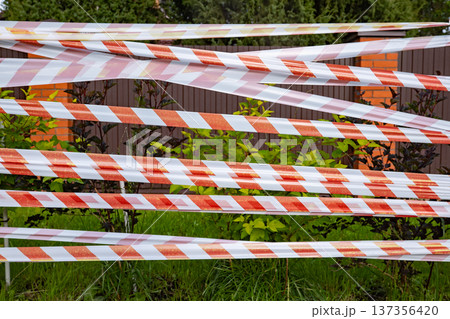 Red and white striped barrier tape creating a restricted area outdoors Red and white striped barrier tape creating a restricted area outdoors 137356420