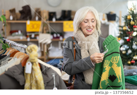 Positive mature woman choosing sweater in clothing store Positive mature woman choosing sweater in clothing store 137356652