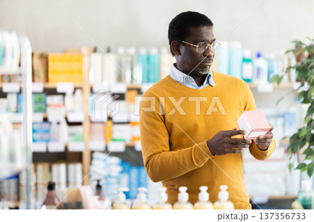 Middle-aged man reading label on box of medicine in drugstore Middle-aged man reading label on box of medicine in drugstore 137356733