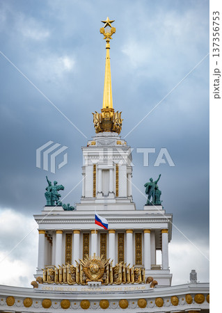 VDNKh central pavilion golden spire with star, statues, and Russian flag in Moscow 137356753
