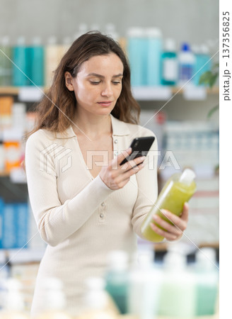 Woman in summer clothes scans code on medicinal shampoo to check expiration date Woman in summer clothes scans code on medicinal shampoo to check expiration date 137356825