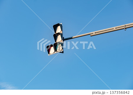 Traffic light with green arrow signal against clear blue sky, directing onward movement Traffic light with green arrow signal against clear blue sky, directing onward movement 137356842