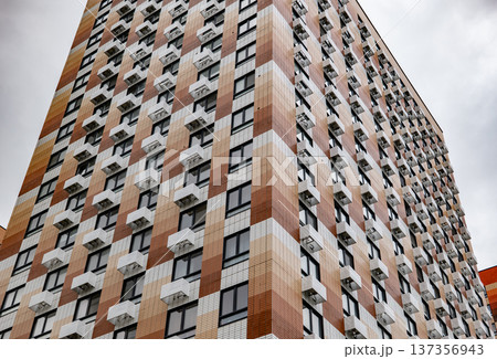 Modern building facade with checkerboard pattern, many windows and air conditioners Modern building facade with checkerboard pattern, many windows and air conditioners 137356943