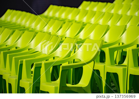 Bright green plastic chairs arranged in rows creating repetition and pattern 137356969