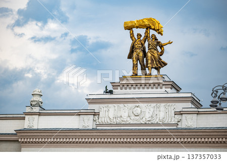 Worker and collective farm woman golden statue on VDNKh Pavilion against sky 137357033