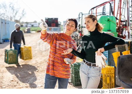 Two interested female farmers talking outdoors near farm machine Two interested female farmers talking outdoors near farm machine 137357059