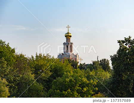 Russian Orthodox church dome rising above green trees in a city park Russian Orthodox church dome rising above green trees in a city park 137357089