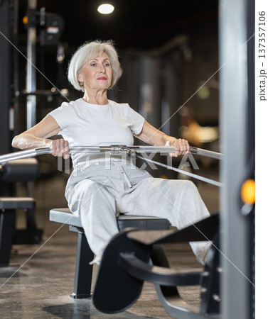 Senior woman training with seated cable row machine at gym Senior woman training with seated cable row machine at gym 137357106