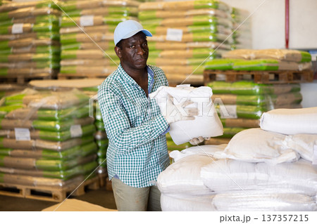 Man working in warehouse, lifting heavy bag Man working in warehouse, lifting heavy bag 137357215