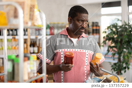African man buyer select choose thoughtfully at bottles of different sauces 137357229