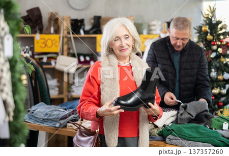 Mature woman standing on the background of a Christmas tree and choosing platform boots 137357260