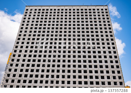 Urban development constructing large building with grid pattern windows under blue sky 137357288
