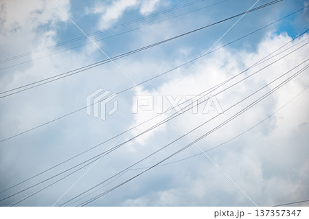 Power lines drawing across cloudy blue sky, representing modern connection and infrastructure 137357347