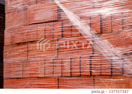 Building materials: new red bricks stacked on a pallet, wrapped in clear plastic Building materials: new red bricks stacked on a pallet, wrapped in clear plastic 137357387