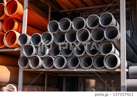PVC drainage pipes stacked on shelves in a warehouse, ready for construction projects 137357421