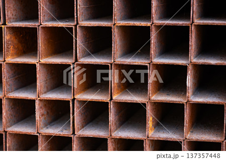 Stacked rusty square metal pipes forming an industrial grid pattern texture Stacked rusty square metal pipes forming an industrial grid pattern texture 137357448