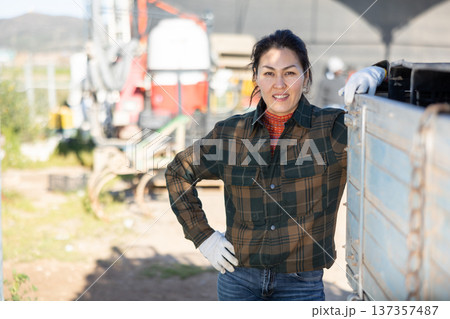 Portrait of positive female tractor driver in farm backyard 137357487