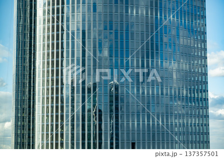 Modern skyscraper facade reflecting blue sky and clouds in glass windows 137357501
